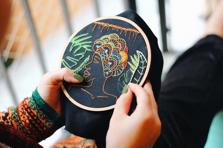 Hands working a stitch on blue and white fabric held taut in an embroidery hoop