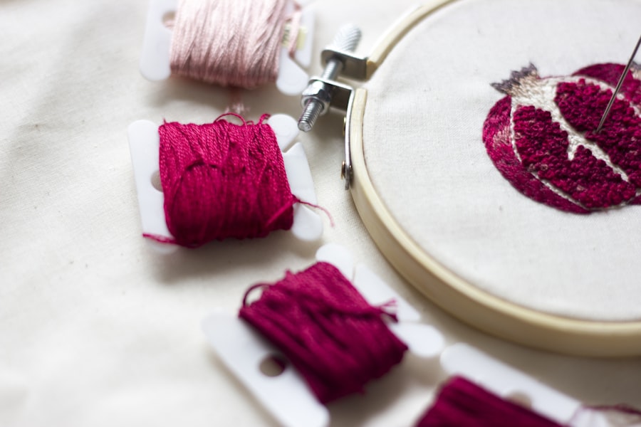 Pink monogram thread work in a round embroidery hoop on white fabric