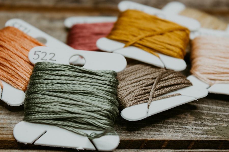 Green and yellow embroidery thread coiled on a warm wooden studio table