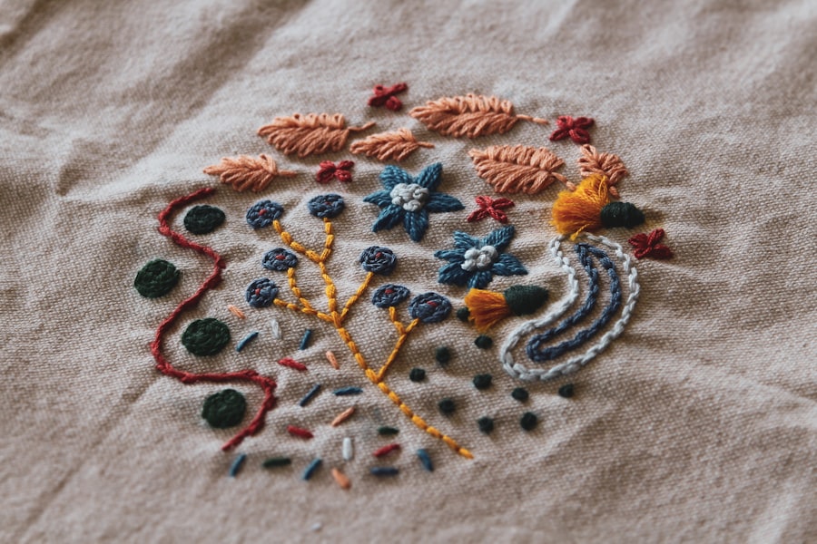 Hand-embroidered floral motif on natural linen in coral, navy and gold threads