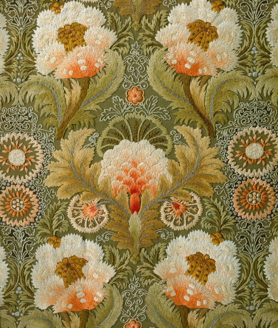 Large floral machine embroidery in cream and coral on deep green fabric
